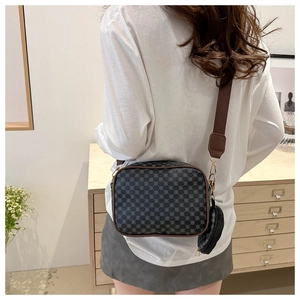 Detail of checkered crossbody camera bag with round coin purse and wide strap on model