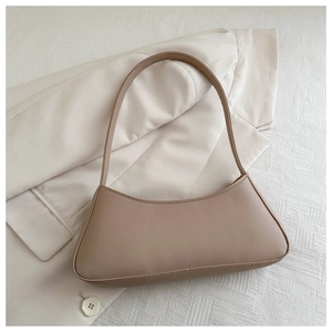 Minimalist beige bow-shaped shoulder bag shown on textured white background fabric