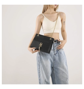 Detail of black quilted leather shoulder bag with gold chain strap and fashion logo