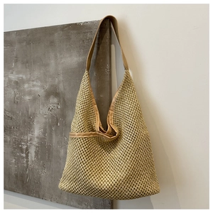 Détail du sac cabas en paille tissée avec anses en cuir brun sur mur moderne