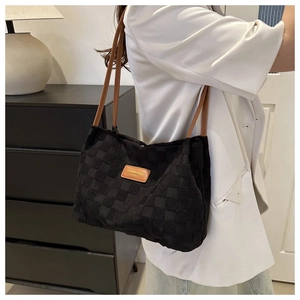 Detail of checkered woven nylon tote bag featuring brown leather straps and fashion label