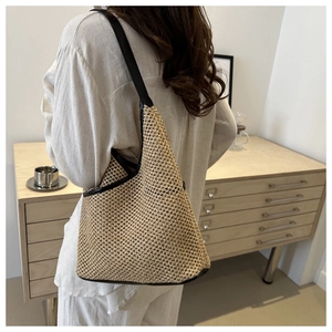 Detail of straw woven shoulder bag with black leather straps and precise weaving texture