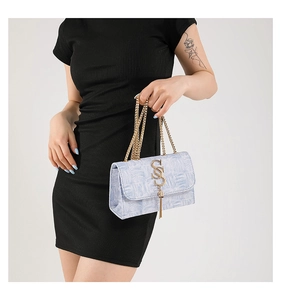 Détail d'un sac bandoulière bleu clair avec logo CSS doré et pendentif pompon élégant