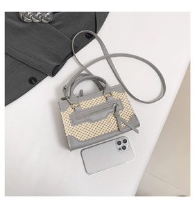 Détail du mini sac patchwork en cuir et paille avec franges et téléphone pour l'échelle