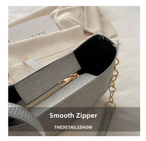 Détail macro d'un sac argenté à paillettes avec fermeture éclair dorée et chaîne de luxe