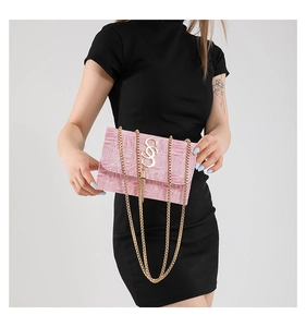 Détail du sac à rabat rose gaufré avec bandoulière chaîne dorée et pompon métallique