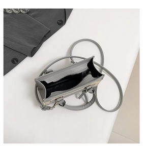 Vue détaillée du sac à bandoulière en cuir gris et tissu tissé avec fermeture éclair