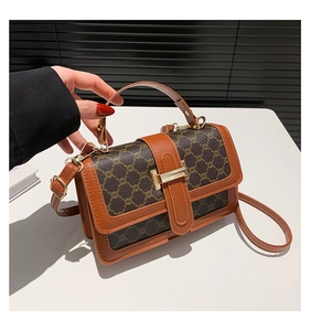 Détail du sac bandoulière vintage montrant le motif monogramme brun et la boucle dorée