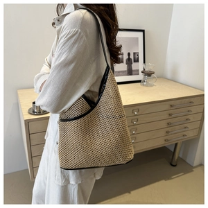 Detailed texture of hand-woven straw bucket bag with contrasting black leather edge trim