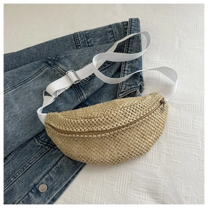 Détail d'un sac banane en paille tressée avec bandoulière blanche sur du denim