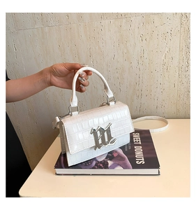 Close-up of white crocodile pattern leather handbag with silver metallic M-lock buckle