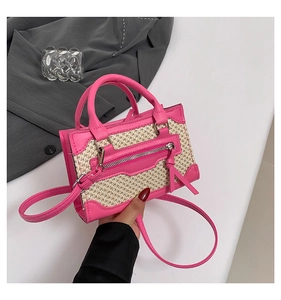 Détail d'un mini sac en cuir rose et paille tressée avec pompons et bandoulière