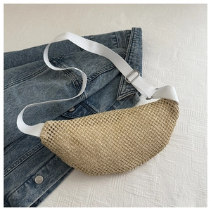 Détail du sac demi-lune en paille tressée avec bandoulière blanche et boucle argentée