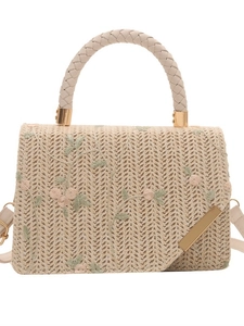 Straw handbag with pink floral embroidery and top handle on white background