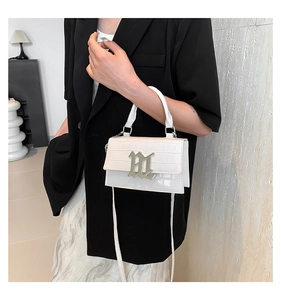 Detail of white patent leather crossbody bag with crocodile pattern and silver metal logo