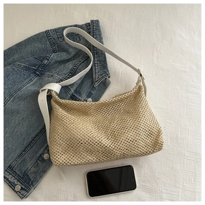 Détail macro du tissage en paille avec bandoulière en cuir blanc sur un sac fourre-tout