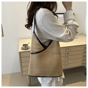 Detail of hand-woven straw bucket bag with contrasting black PU leather strap and trim