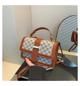 Détail du sac bandoulière en tissu rétro avec bordure en cuir brun et boucle dorée