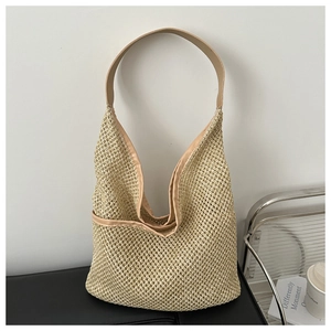 Gros plan sur la texture tressée et les anses en cuir du sac seau beige