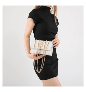Détail d'un sac bandoulière beige à texture crocodile avec chaîne dorée et boucle