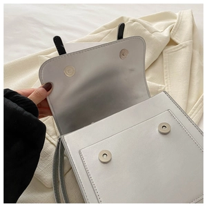 Detail of light grey leather handbag showing double magnetic buckles and front pocket