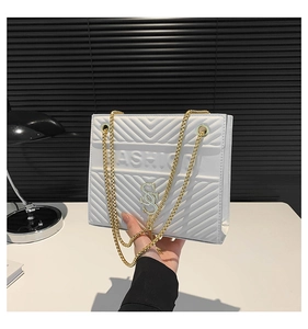 Detail of white quilted handbag with gold chain strap and textured diamond pattern