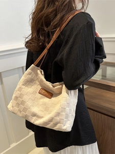 Chic beige woven tote bag with brown leather straps shown on a model from a side angle