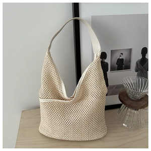 Détail de la texture en maille tissée beige et de la bandoulière en cuir lisse du sac