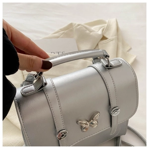 Detail of silver PU leather handbag with metallic finish and butterfly metal clasp