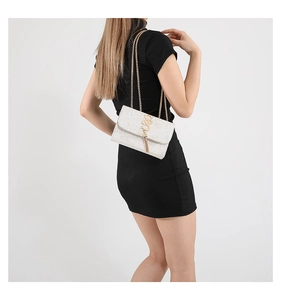Détail du sac bandoulière blanc tissé avec chaîne dorée et gland en métal sur mannequin