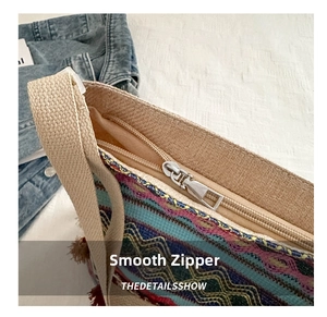 Detailed view of the smooth metal zipper and tassel on the woven ethnic tote bag