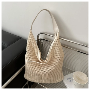 Gros plan sur la maille tissée crème et les détails en cuir de ce sac seau à bandoulière chic