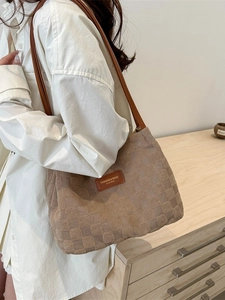 Brown checkerboard textured tote bag with leather straps and minimalist brand patch