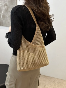 Handwoven straw bucket shoulder bag in natural tone shown from a back perspective