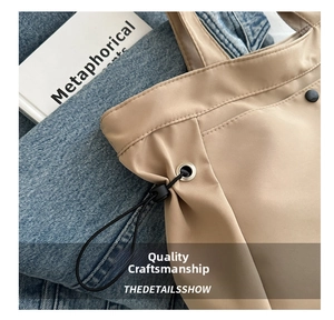 Detail of reinforced stitching, dark metal snap button and drawstring on beige tote bag