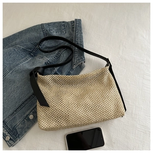 Détail du sac cabas tissé beige avec bretelles noires et texture en maille sur tissu