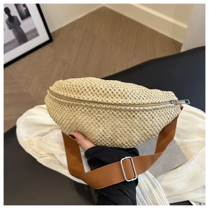 Detail of woven straw mini chest bag with beige texture and brown nylon strap