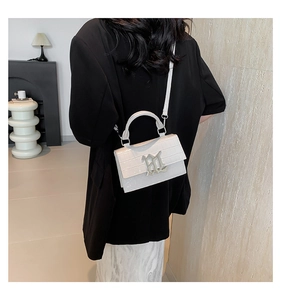Detail of white crocodile pattern shoulder bag with silver M buckle on black blazer