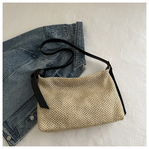 Détail de la texture d'un sac cabas en paille tissée avec bandoulière en similicuir