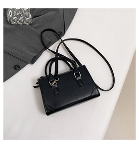Détails du sac carré en cuir noir avec ferrures dorées et fine bandoulière réglable