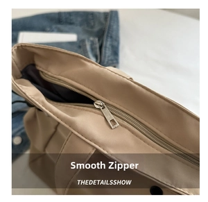 Close-up of smooth metal zipper on beige nylon tote bag with fine texture detail