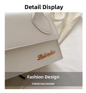 Close-up of white leather handbag with gold metal logo and precise stitching details