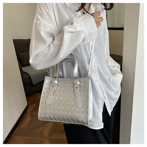 Close-up of silver woven texture and metal rivet handle on fashionable crossbody bag