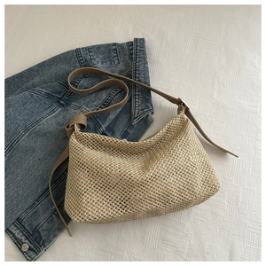 Détail du sac hobo en paille tressée avec bandoulière en similicuir brun et maille
