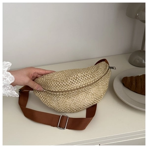 Détail d'un sac banane en paille tressée beige avec sangle en nylon marron et boucle