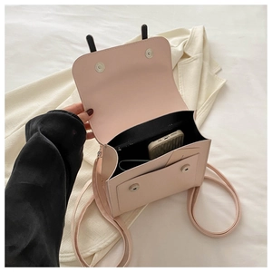 Detail view of pink leather handbag with black ear design, magnetic closure and interior space