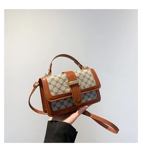 Détail du sac bandoulière vintage avec motif monogramme et boucle métallique dorée