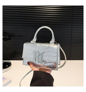 Detail of silver crocodile-embossed handbag featuring metallic luster and metal logo