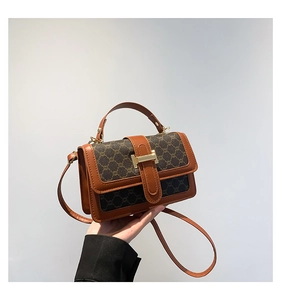 Gros plan d'un sac à main vintage à monogramme marron avec fermoir doré et poignée