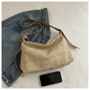 Vue détaillée du cabas en paille tissée beige avec bandoulière en cuir marron réglable